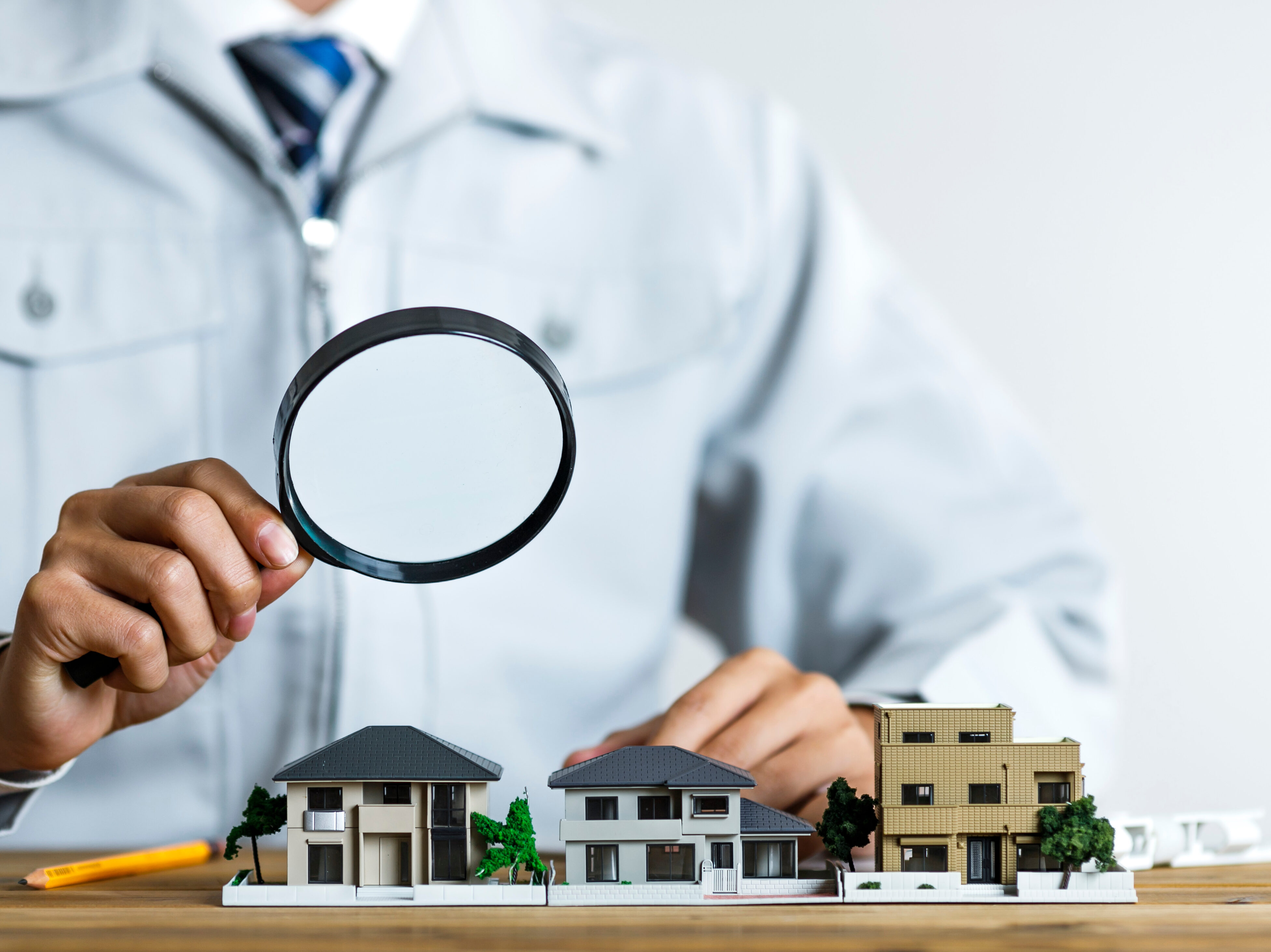 住宅模型をルーペで覗く作業服の男性